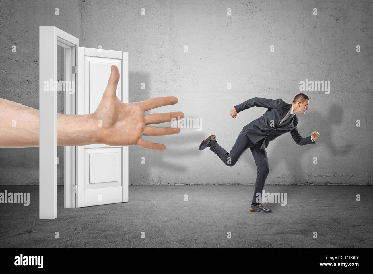 Imprenditore di scappare da una grossa mano fuori da una porta aperta sul muro grigio Sfondo. Foto Stock