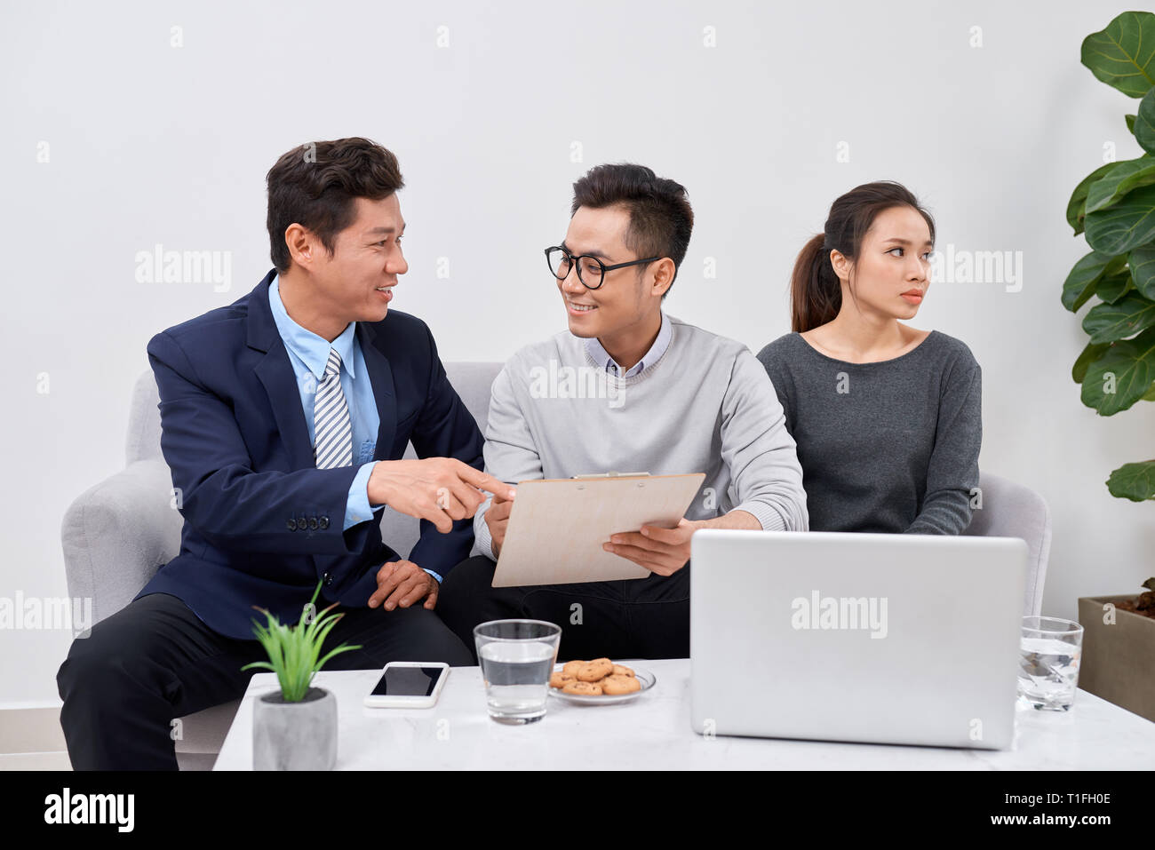 Non è colpa mia! Orinato giovane uomo che parla di psichiatra e gesticolando mentre sua moglie seduta vicino a lui e mantenendo le braccia incrociate Foto Stock
