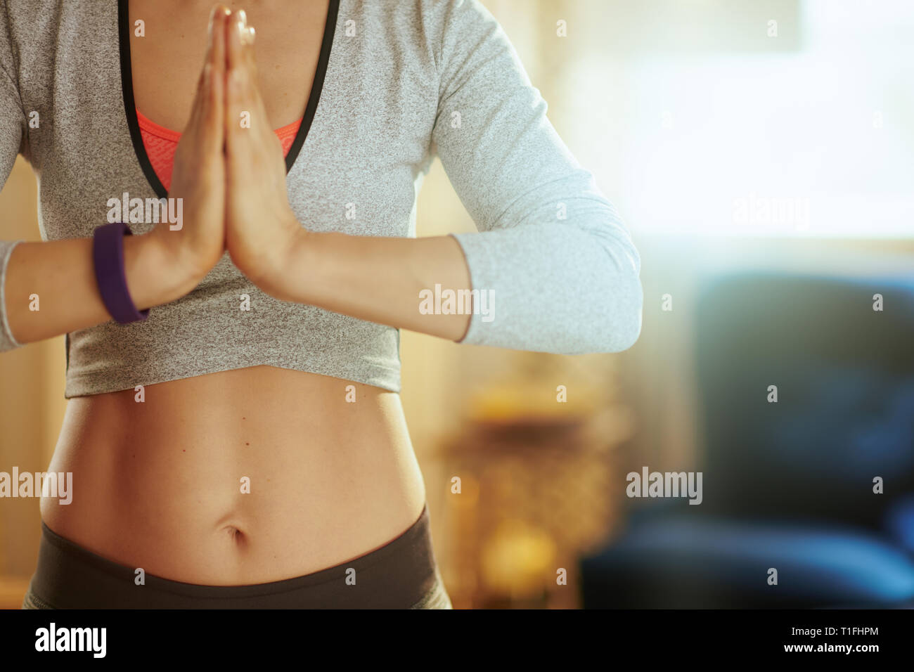 Primo piano sulle mani della donna fitness facendo yoga nella casa moderna. Foto Stock