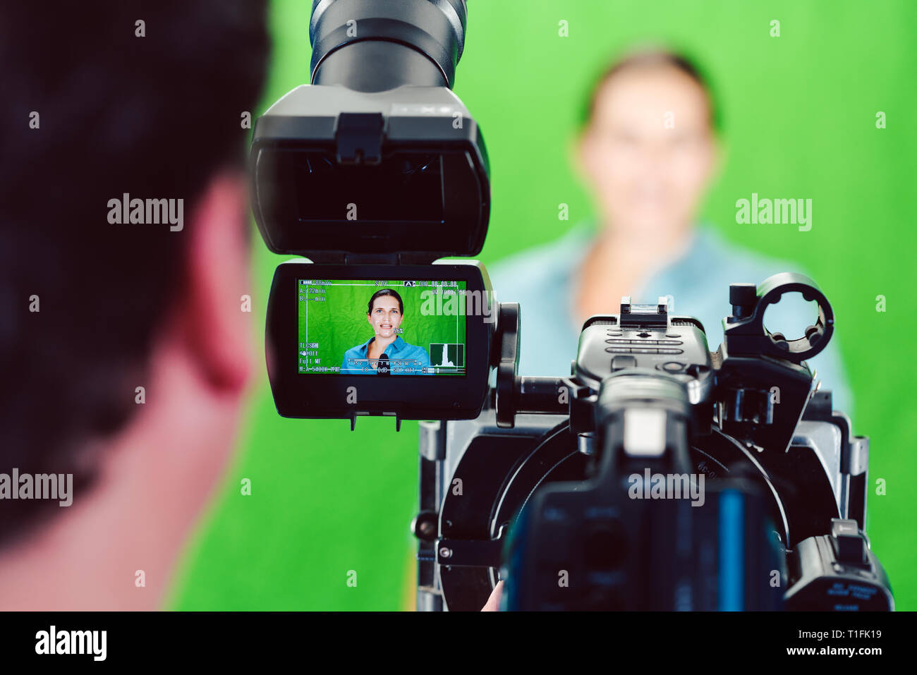 Telecamera puntata una donna di notizie o di reporter in camera verde studio Foto Stock
