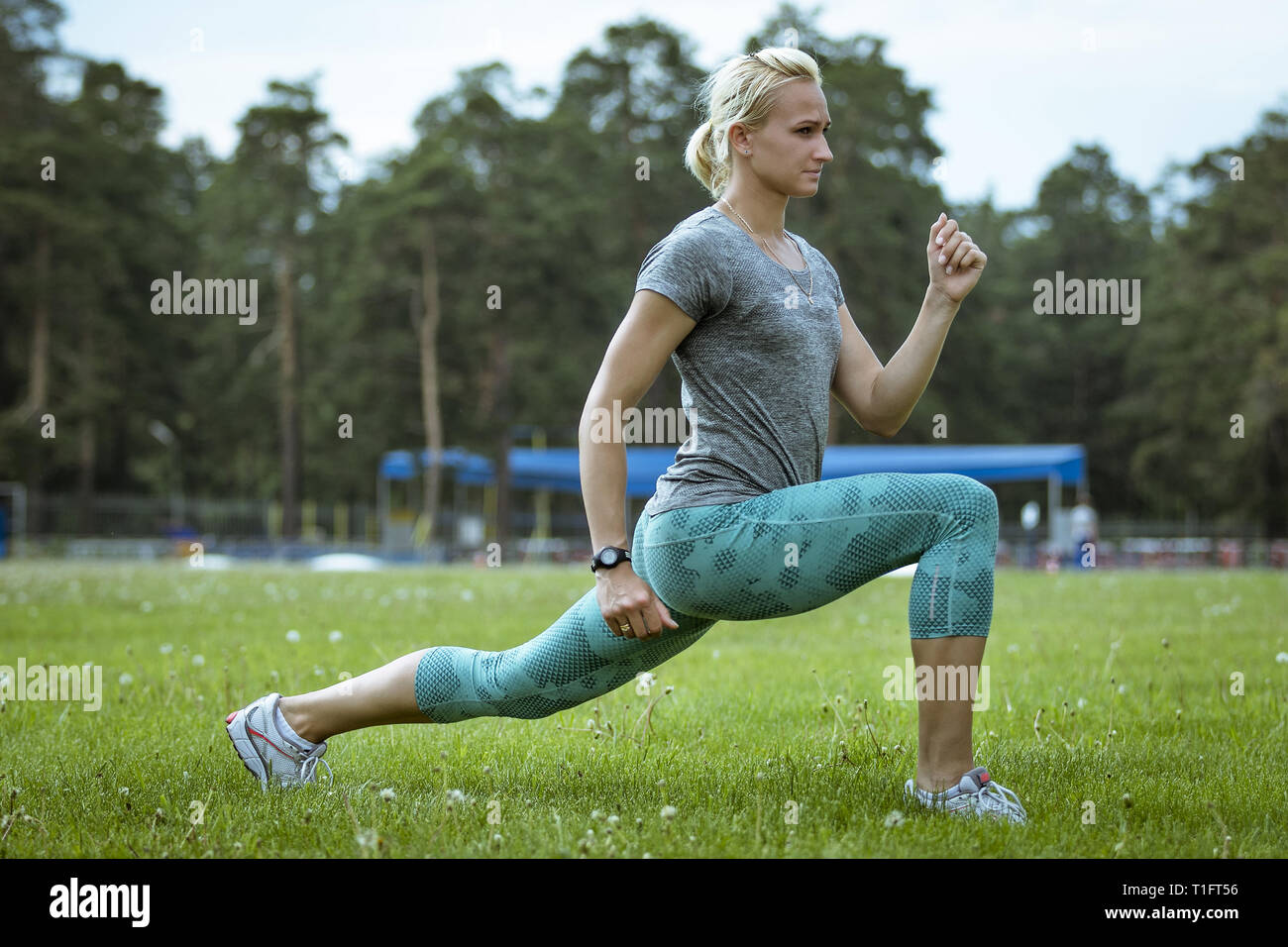 Donna atleta a fare gli esercizi a piedi in erba verde campo Foto Stock