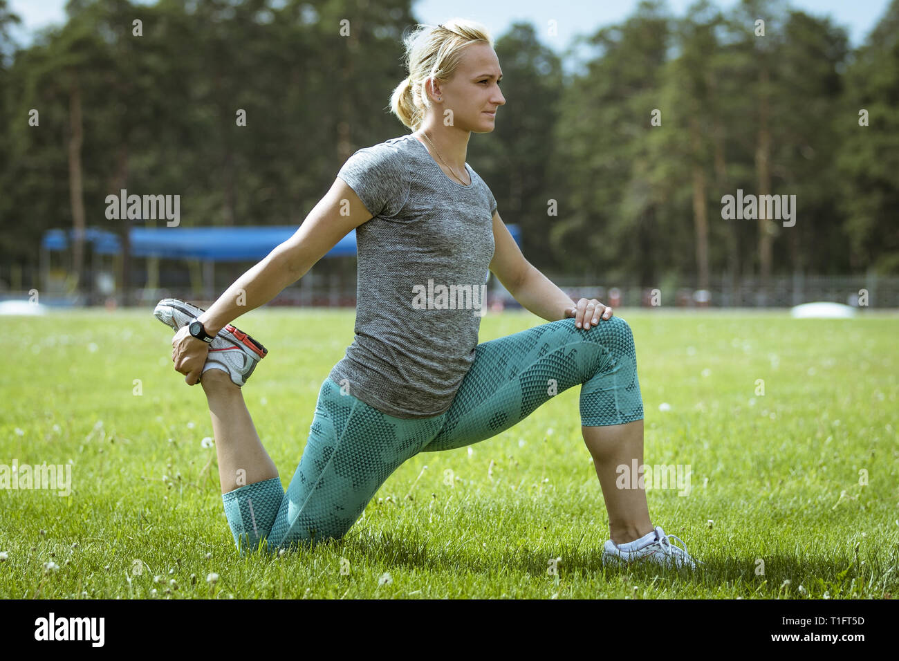 Atleta femminile esercizio stretching gambe su erba verde Foto Stock