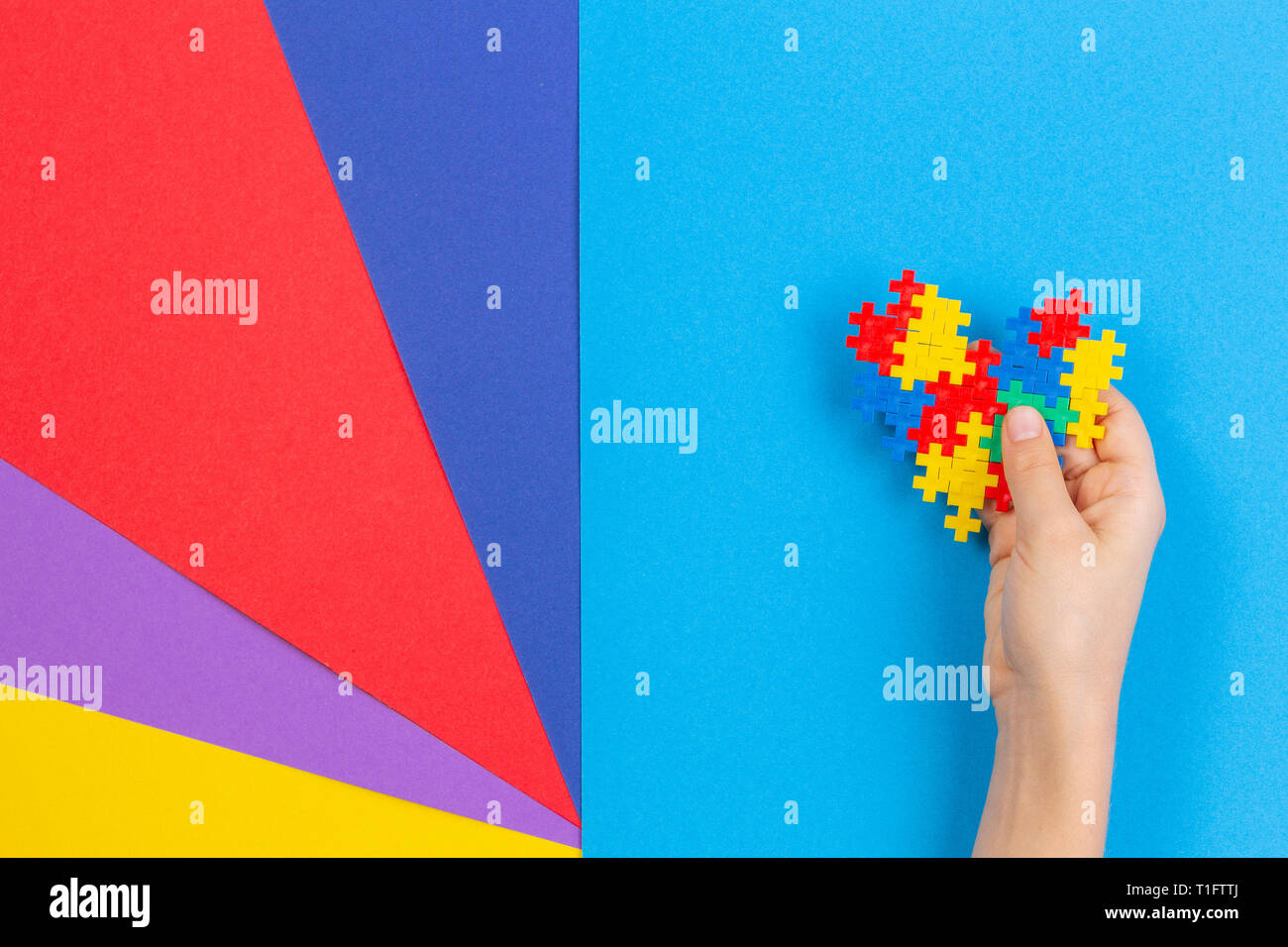 Kid mano azienda cuore colorati su sfondo multicolore. Mondo autismo consapevolezza giorno di concetto Foto Stock