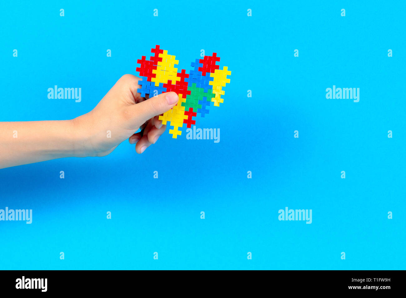 Bambino mano azienda cuore colorati su sfondo blu. Mondo autismo consapevolezza giorno di concetto Foto Stock