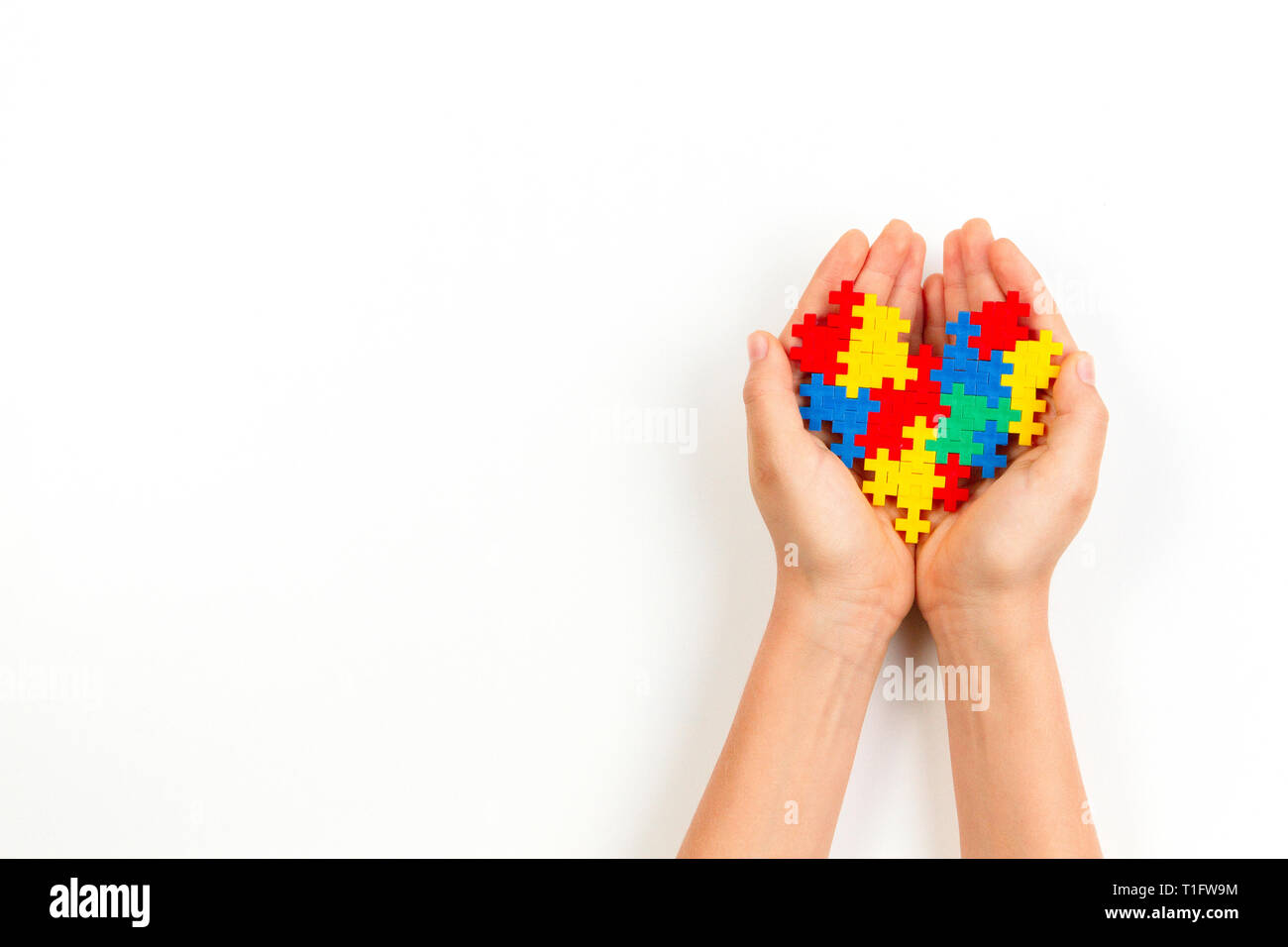 Bambino mano azienda cuore colorato su sfondo bianco. Mondo autismo consapevolezza giorno di concetto Foto Stock