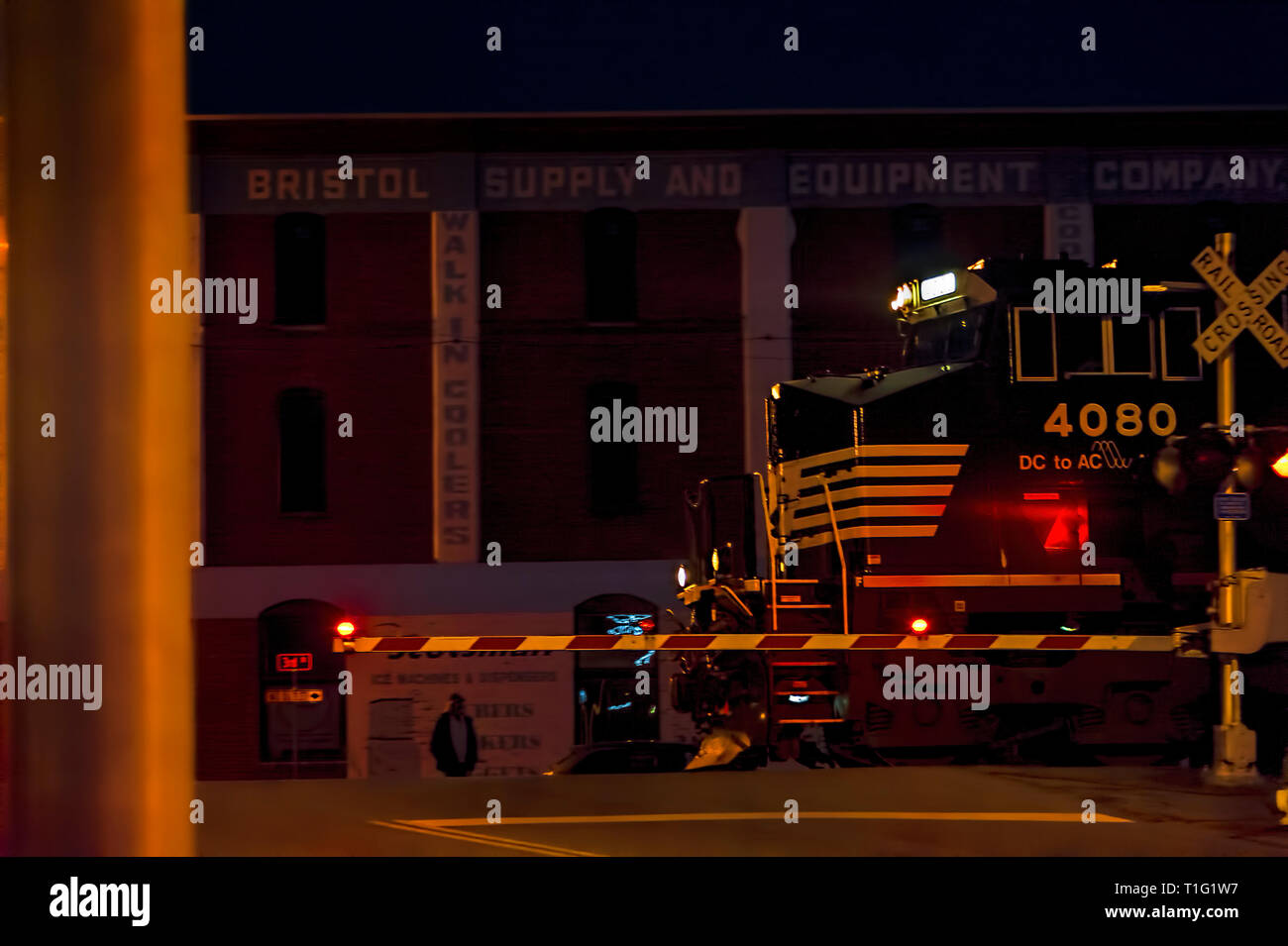 Bristol, Virginia/Tennessee,USA - Marzo 20,2019: Un treno motore anticipi su State Street attraversamento ferroviario di notte a Bristol. Foto Stock