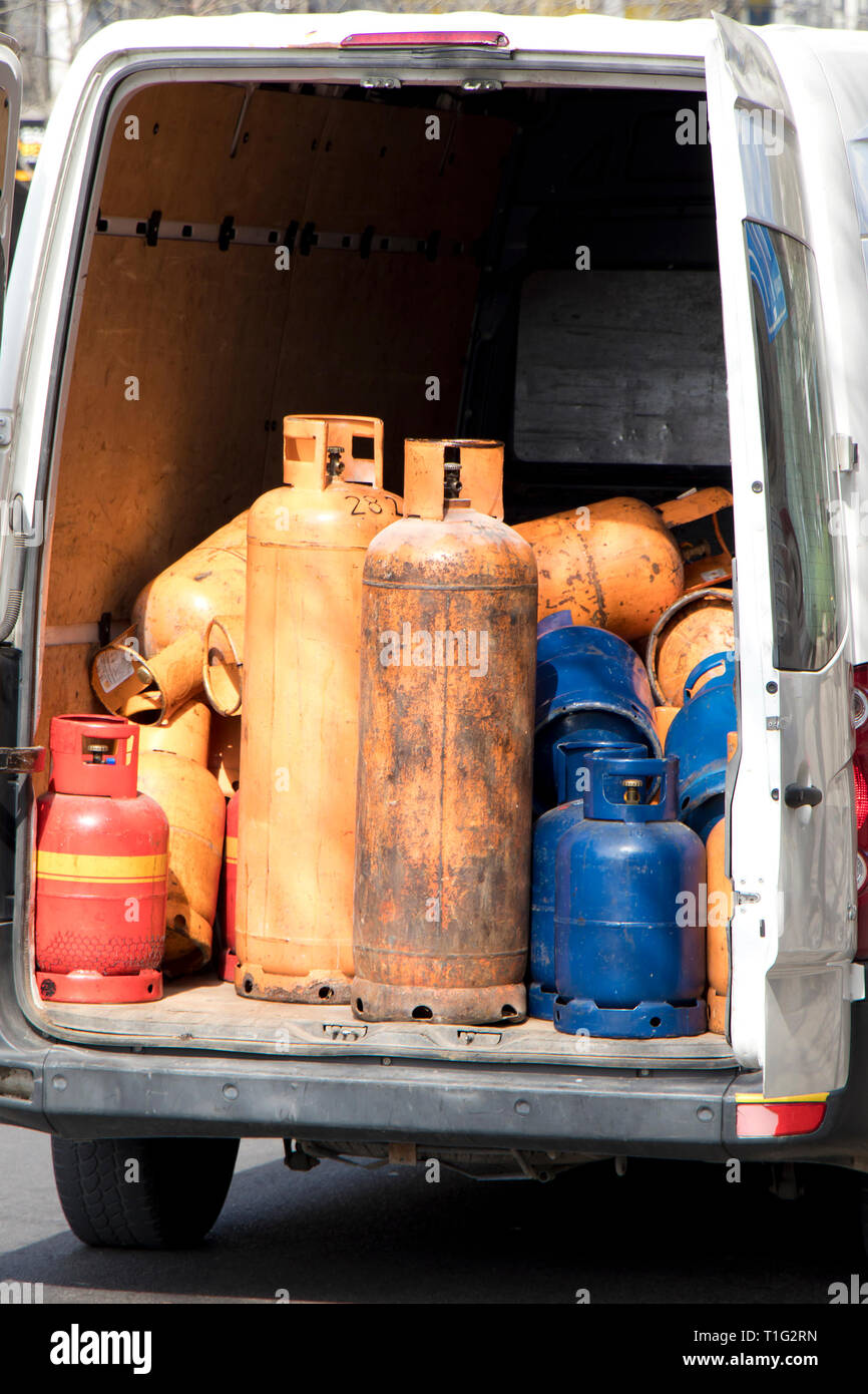 Colore diverso e la dimensione del cilindro di bombole a gas in una consegna parcheggiata van trunk per riempire e alimentazione Foto Stock