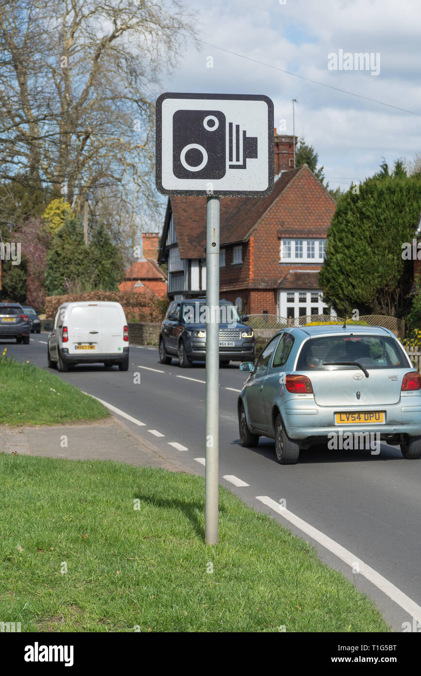 Velocità segno della fotocamera sulla trafficata strada di villaggio o street, Surrey, Regno Unito, con il passaggio del traffico. La sicurezza stradale concetto. Foto Stock