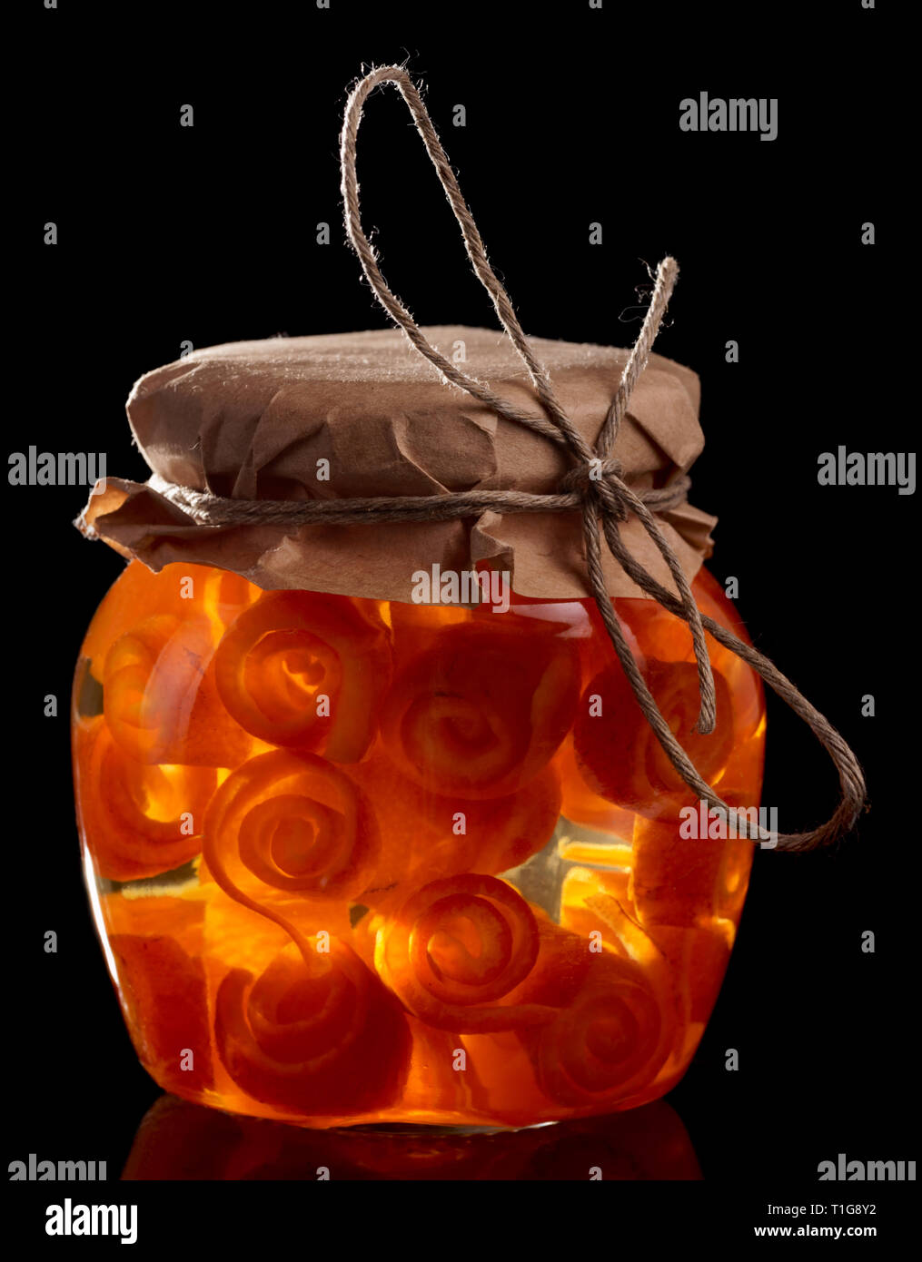Vaso di vetro con la scorza degli agrumi conserva isolati su sfondo nero Foto Stock