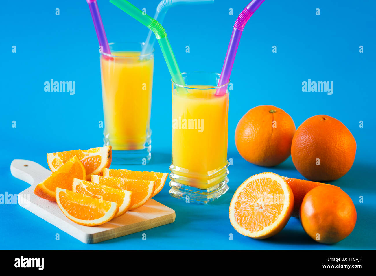 Succo di arancia e arance isolato su sfondo blu Foto Stock