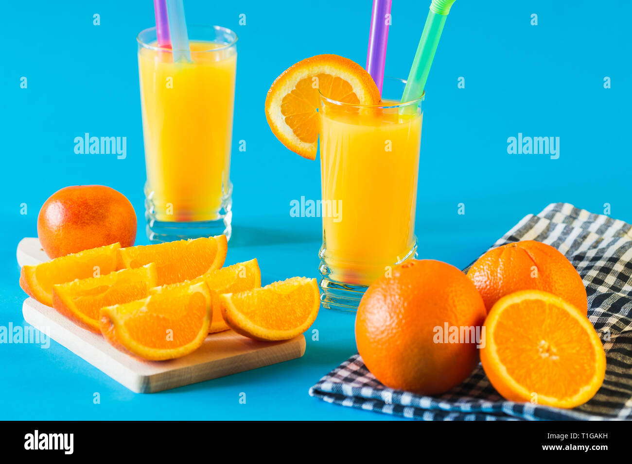 Succo di arancia e arance isolato su sfondo blu Foto Stock