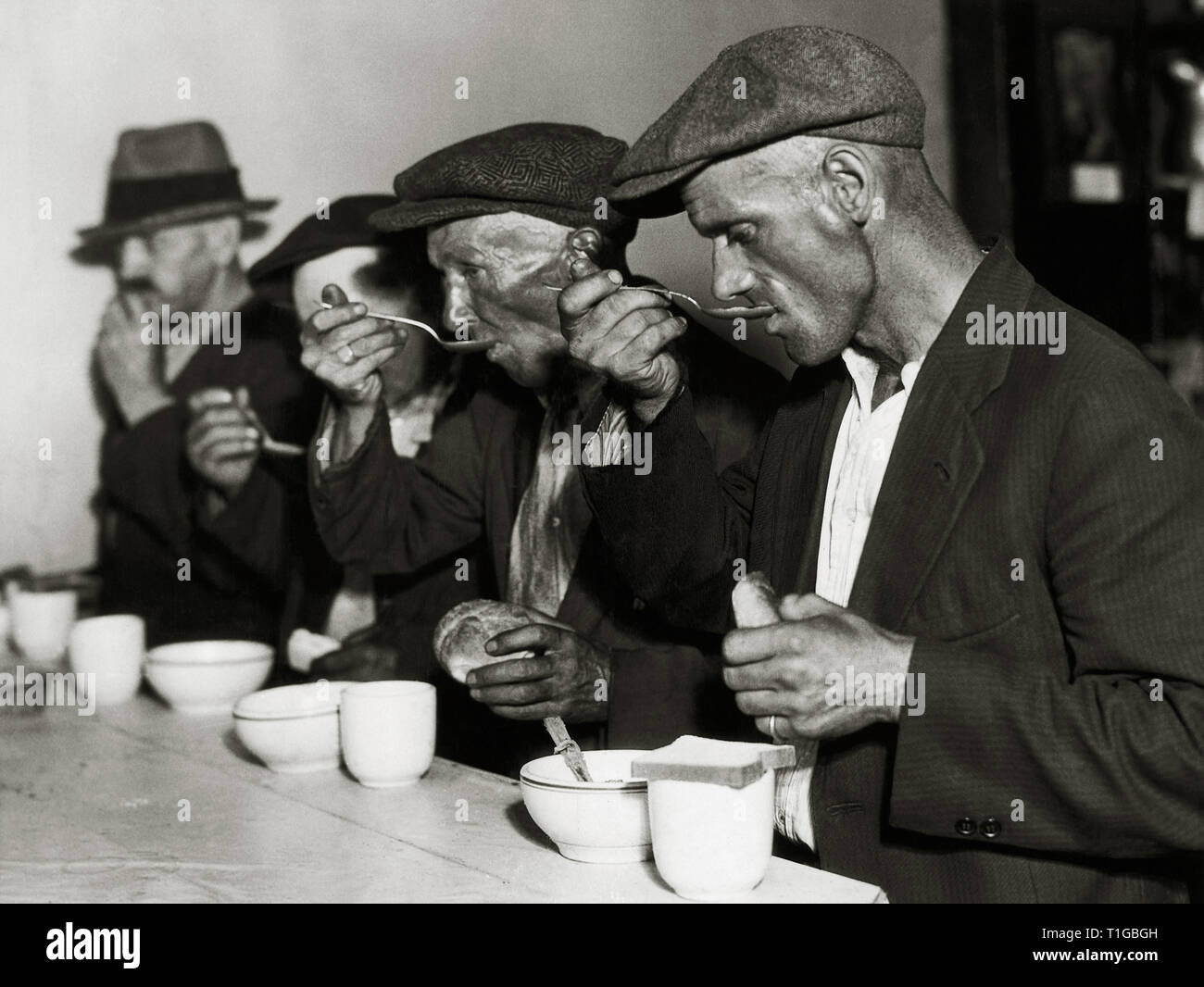 Uomini di mangiare il pane e la minestra in una linea di pane durante la Grande Depressione negli Stati Uniti, circa 1929 Riferimento File # 1003 730THA Foto Stock
