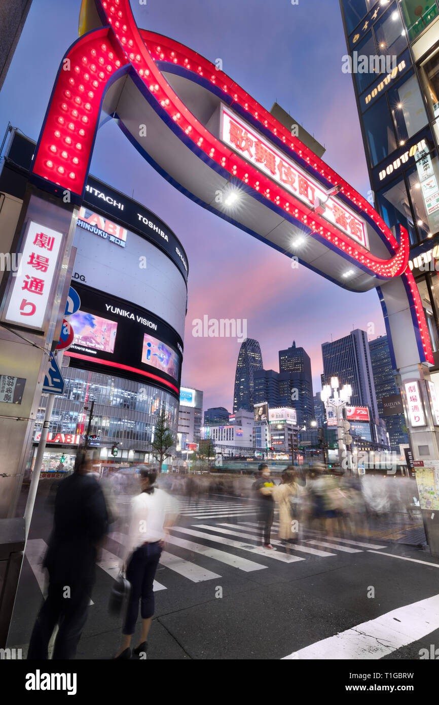 Le persone in attesa di attraversare una strada trafficata di notte sul bordo di Kabukicho, Tokyo, Giappone Foto Stock