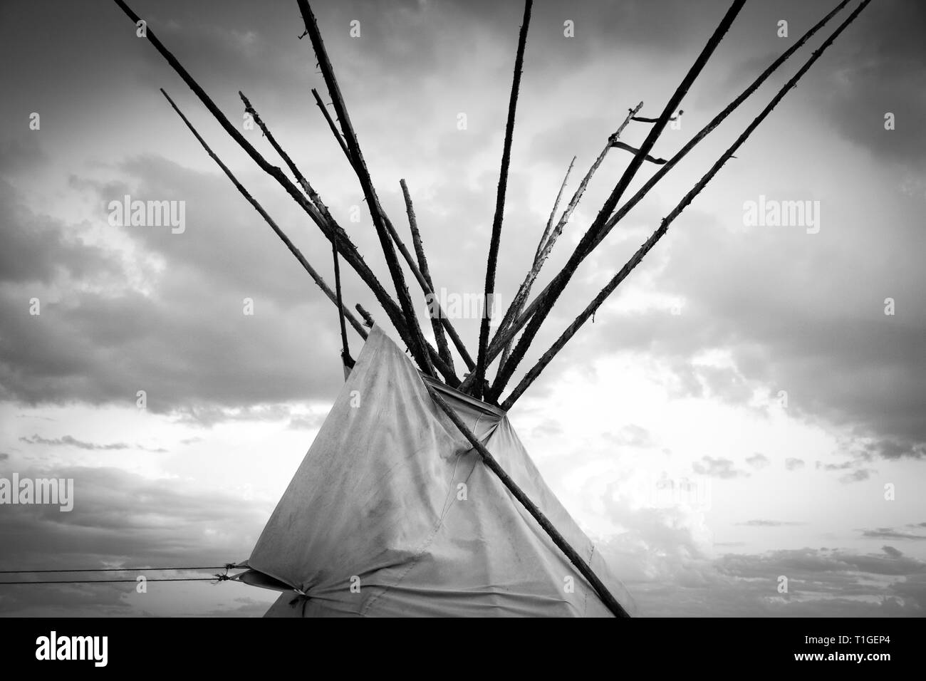 Un tagliato vicino fino in bianco e nero vista della sommità di un tende Tepee con drammatica sky in pianure occidentali al tramonto negli Stati Uniti Foto Stock