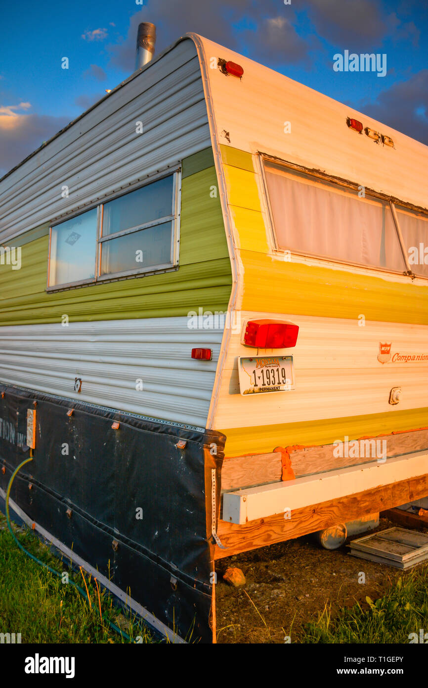 Un vecchio camper trailer sembra aver visto giorni migliori ed è ora disattivato la griglia vivere al tramonto nel Montana, USA Foto Stock
