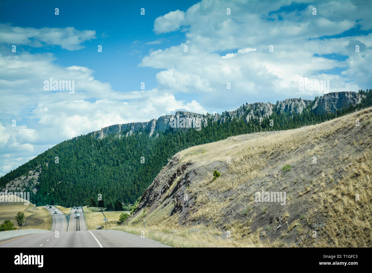 Vista dalla I-90 freeway di un avvicinamento diviso autostrada attraverso le montagne in Big Sky Country, Western Montana, USA Foto Stock