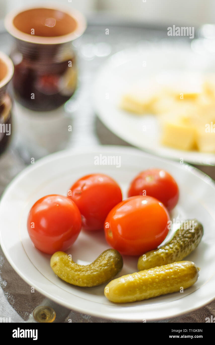 Cetrioli sottaceto e pomodori su un tavolo serviti in una piastra bianca Foto Stock