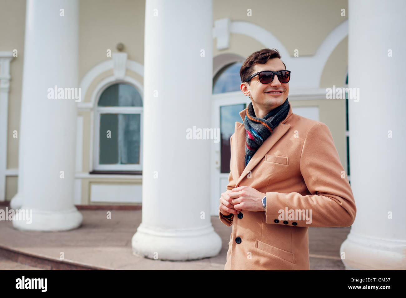 Giovane uomo elegante a piedi nella città. Bel ragazzo indossa abiti classici e accessori. Street fashion. Uomo pulsanti di fissaggio Foto Stock