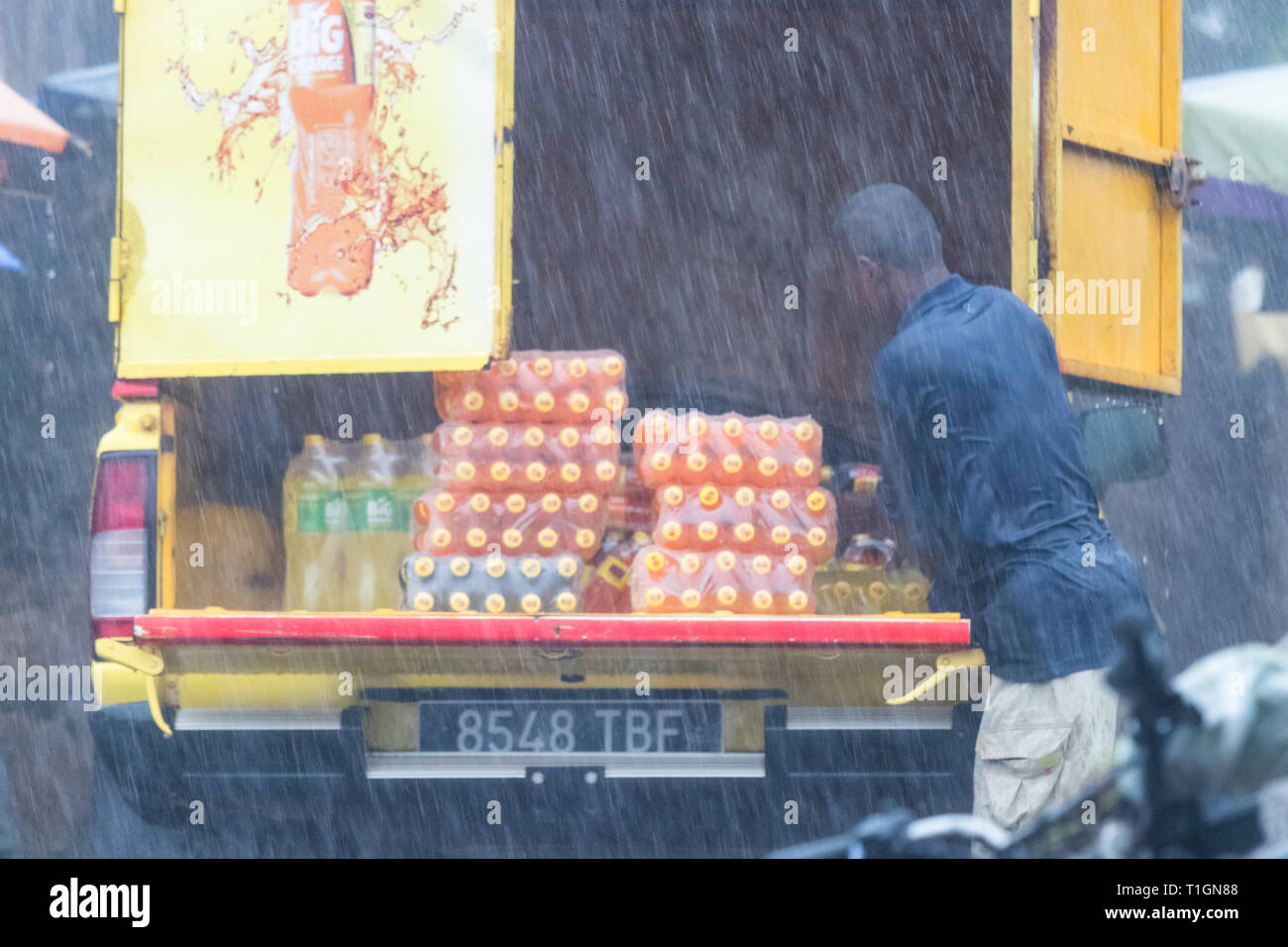 Nosy Be, Madagascar - Gennaio 17th, 2019: un uomo lo scarico soft drink bottiglie da un carrello sotto una forte pioggia a Nosy Be, Madagascar. Foto Stock