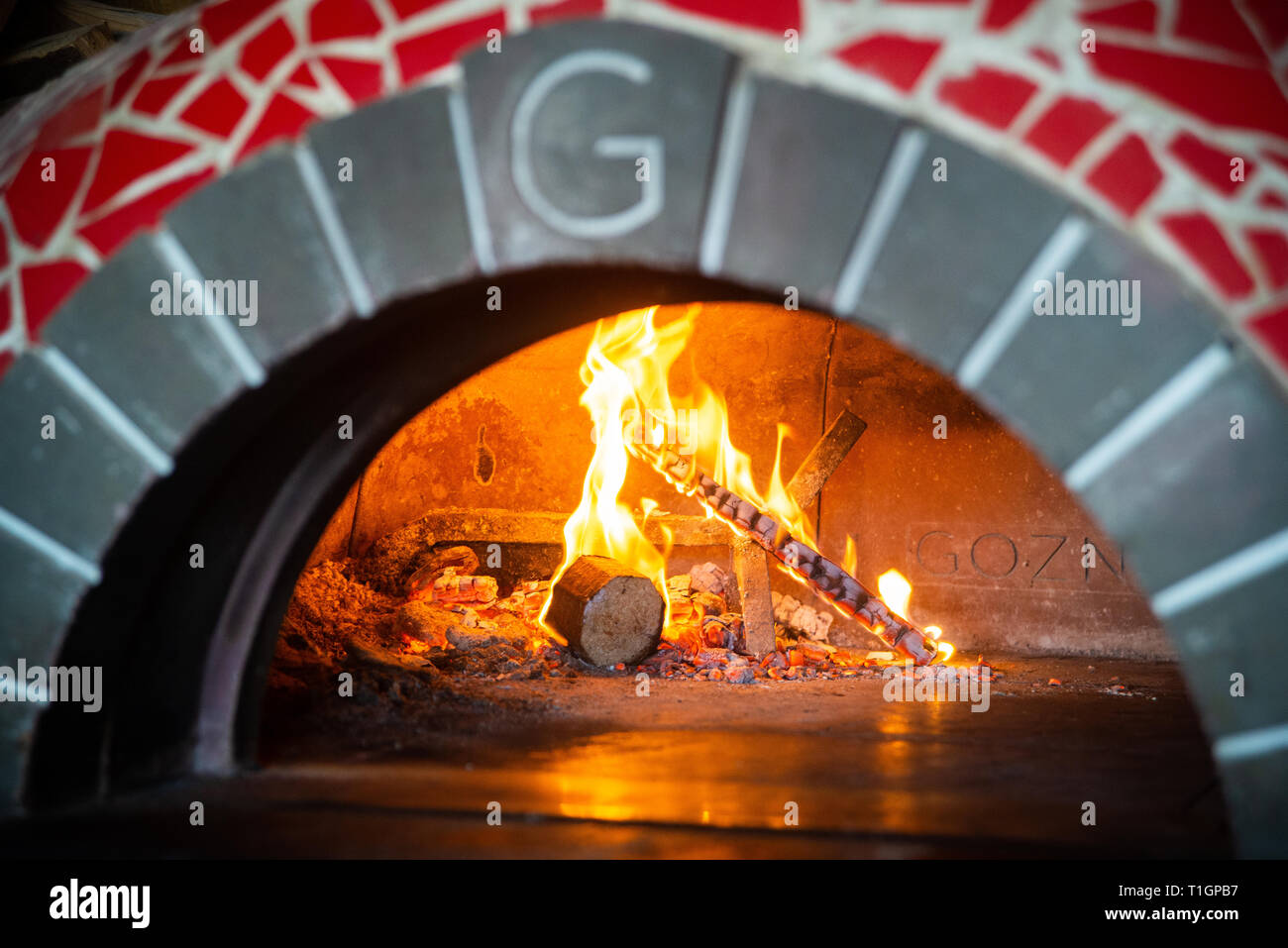 Close up di un tradizionale a legna per pizza italiana forno rosso con piastrelle a mosaico in una pizzeria trattoria Foto Stock