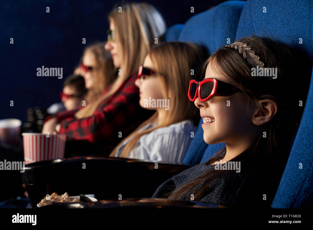 Fila di persone in cinema seduta, guardando un film o cartone animato. Carino e bella ragazza che indossa in occhiali 3d godendo di premiere del film. Foto Stock