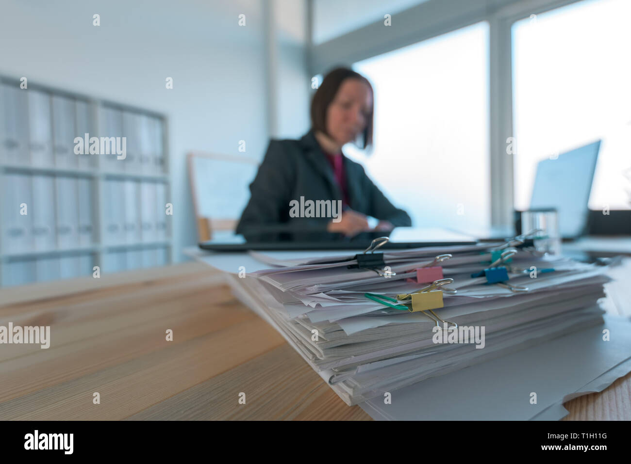 Imprenditrice occupato facendo la documentazione in ufficio presso il desk riempito con documenti e documentazione Foto Stock