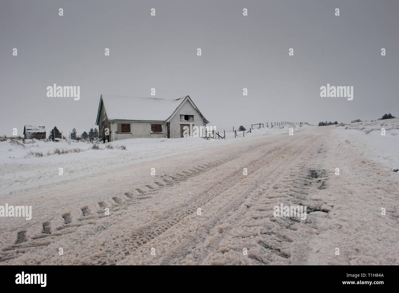 Coperte di neve sulla strada Dartmoor con ex stazione di pompaggio di acqua in shot, spazio di copia Foto Stock