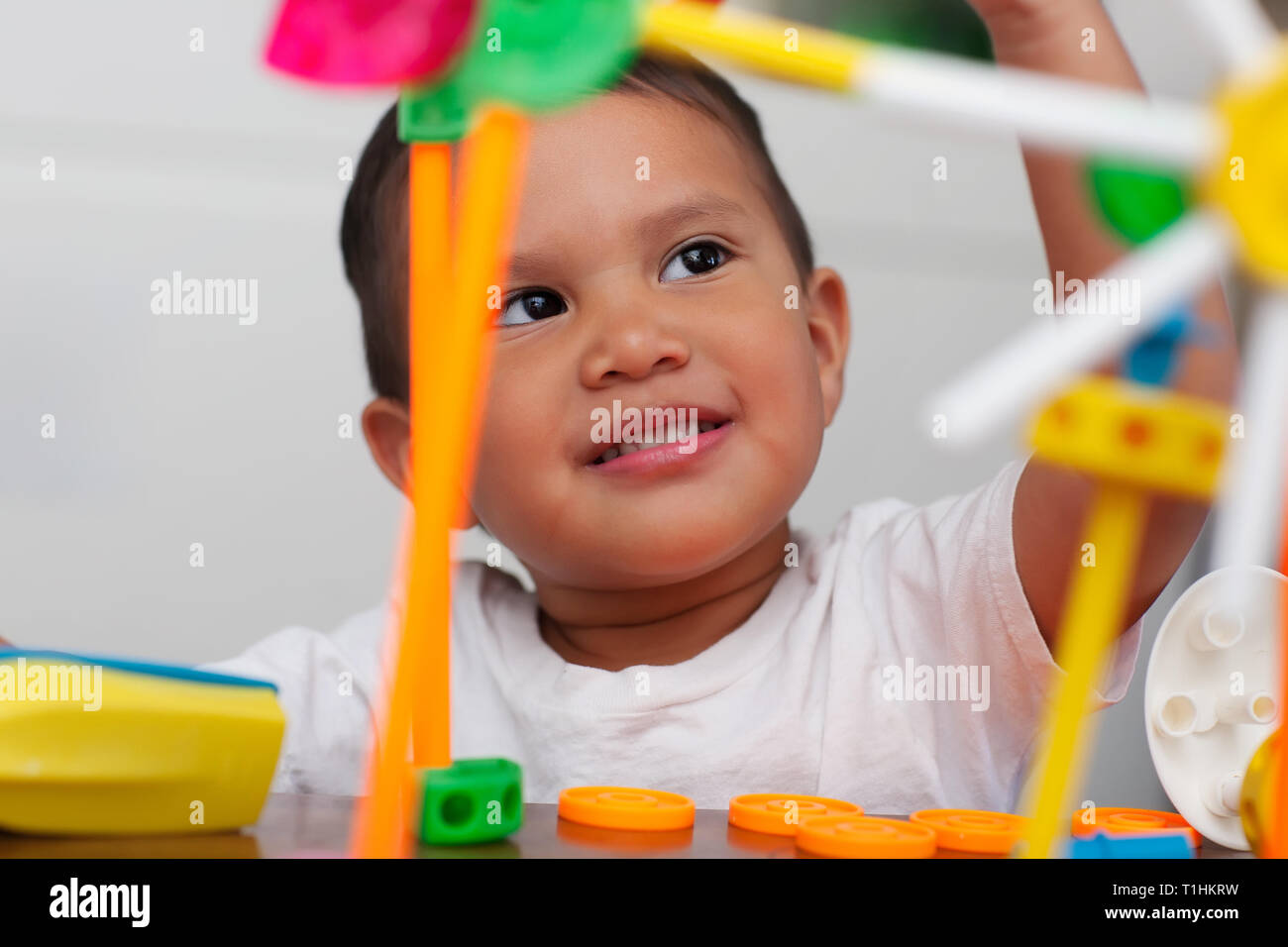 Un simpatico ragazzo giocando con math prescolare manipolativo giocattoli e con un espressione del viso che mostra la meraviglia o pensare. Foto Stock
