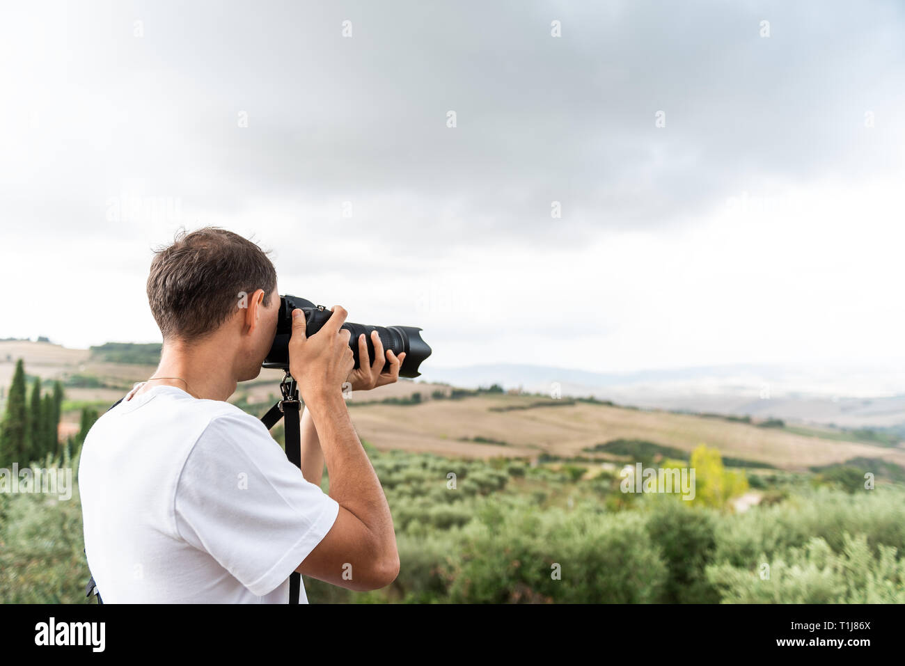 Val D'Orcia campagna in Toscana, Italia, con il verde delle colline con la fattoria del paesaggio e giovane fotografo turistico di scattare una foto con la fotocamera Foto Stock