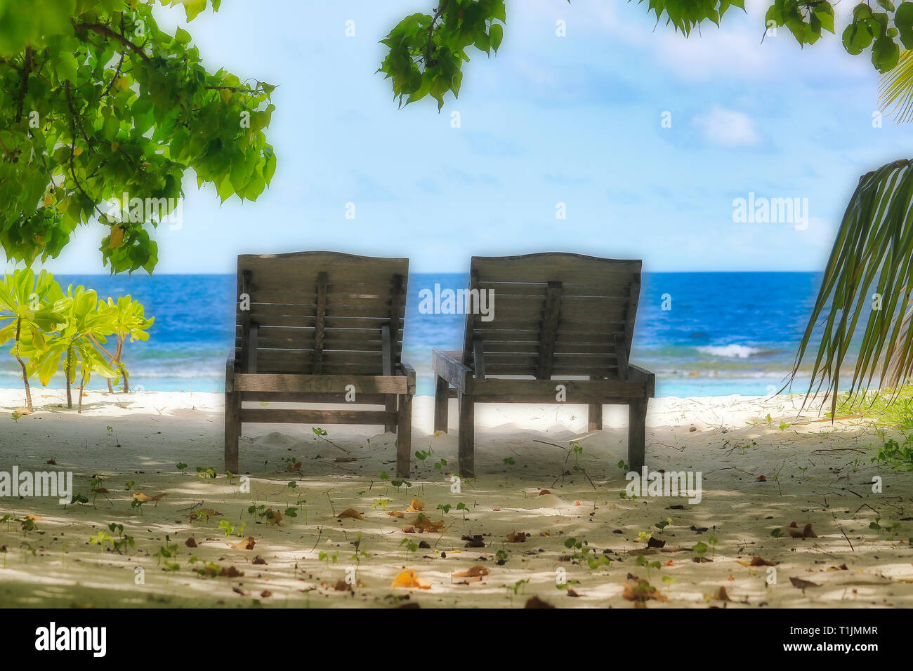 Questa unica immagine mostra due belle vecchio di legno sedie a sdraio sulla spiaggia naturale delle Maldive affacciato sul mare Foto Stock