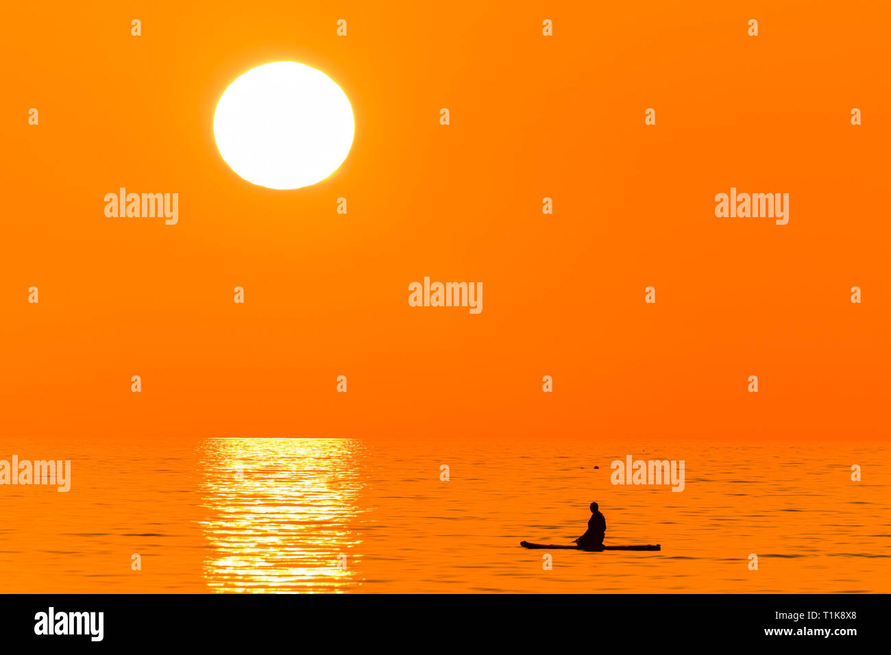 Aberystwyth Wales UK, Mercoledì 27 Marzo 2019 UK Meteo: un bel tramonto , alla fine di un altro giorno di caldo sole primaverile, sagome una persona paddleboarding su te calma piatta mare a Aberystwyth, il Cardigan Bay costa del Galles occidentale. Alta pressione continua a dominare il meteo per gran parte del Regno Unito, con condizioni regolate e chiaro quasi limpido cielo blu foto Keith Morris/Alamy Live News Foto Stock