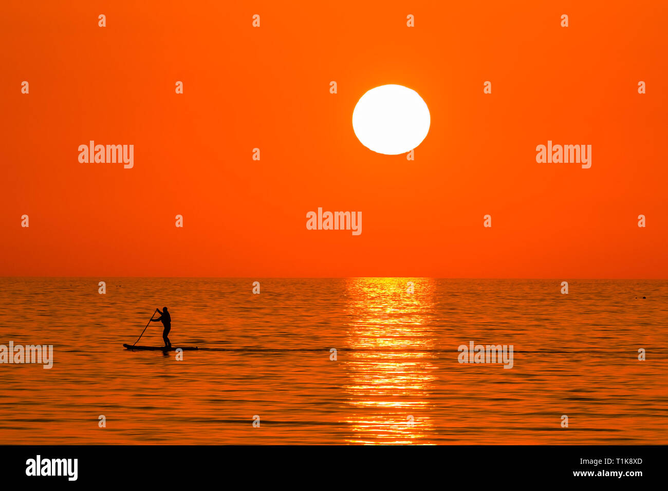 Aberystwyth Wales UK, Mercoledì 27 Marzo 2019 UK Meteo: un bel tramonto , alla fine di un altro giorno di caldo sole primaverile, sagome una persona paddleboarding su te calma piatta mare a Aberystwyth, il Cardigan Bay costa del Galles occidentale. Alta pressione continua a dominare il meteo per gran parte del Regno Unito, con condizioni regolate e chiaro quasi limpido cielo blu foto Keith Morris/Alamy Live News Foto Stock
