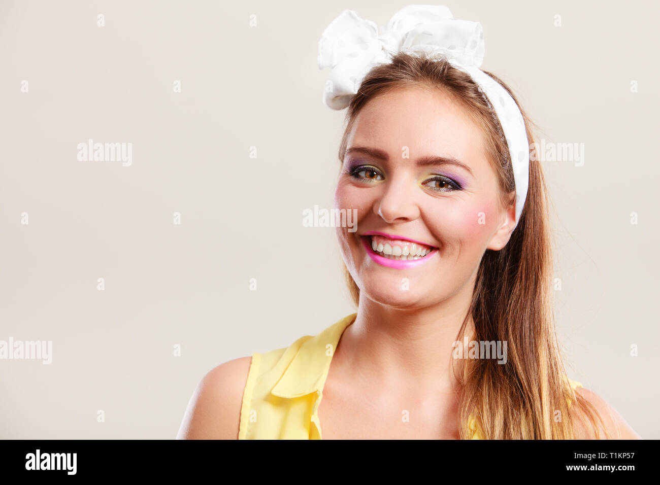Ritratto di sorridenti piuttosto pin up girl con cerchietto per capelli bow. Attraente stupendo giovane donna retrò che pongono in studio. Foto Stock