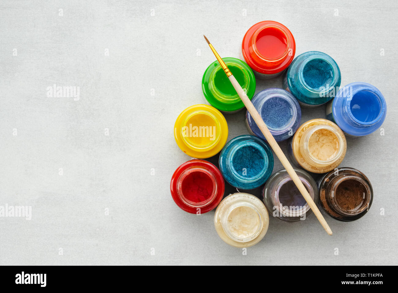 Colorate in vetro colorato o olio, vernici acriliche con spazzola di vernice su uno sfondo grigio con copia spazio, vista dall'alto. Foto Stock