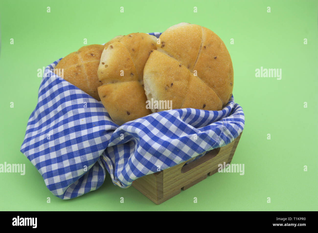 Un paio di pane dolce all'interno di una gabbia in legno e un panno bianco e quadrati blu su sfondo verde Foto Stock