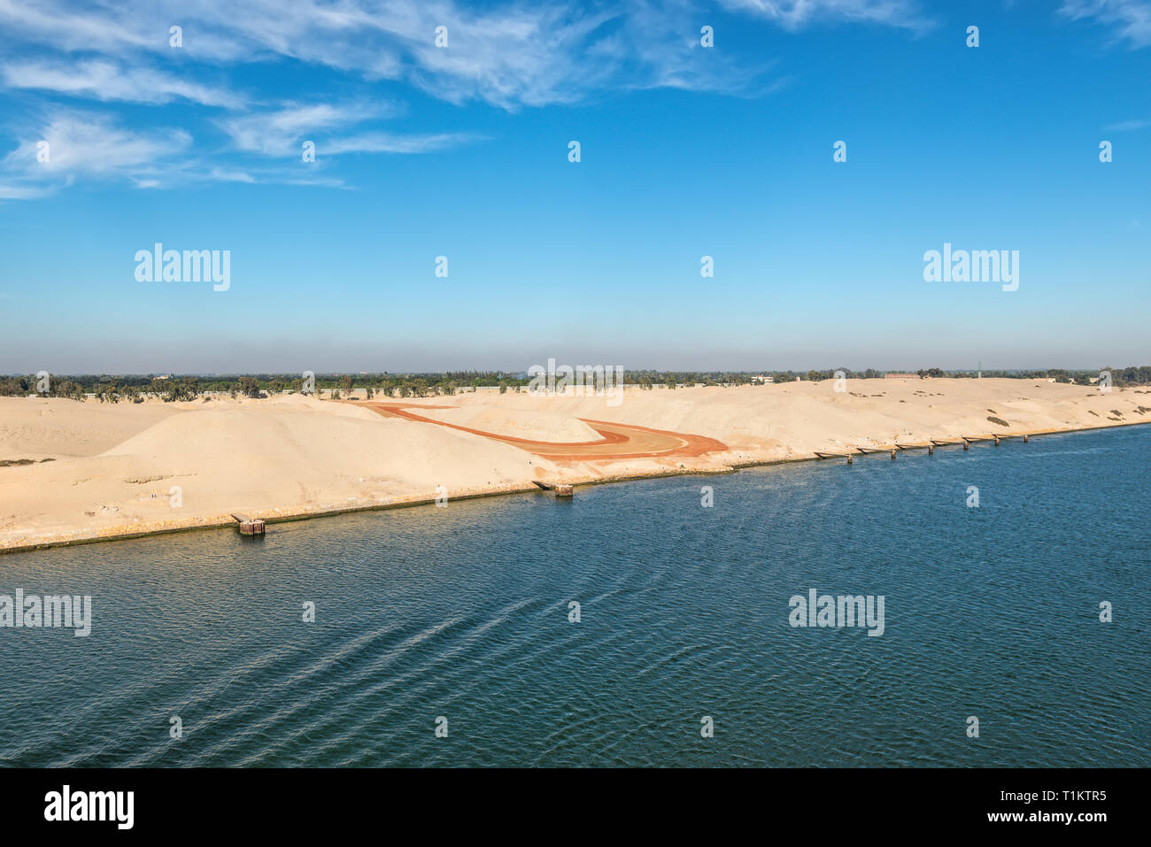 Il lato occidentale del Canale di Suez. Primo piano - Sito in costruzione. In background - ferrovia, edifici e palme. Vista dall'acqua, il canale di Suez Foto Stock