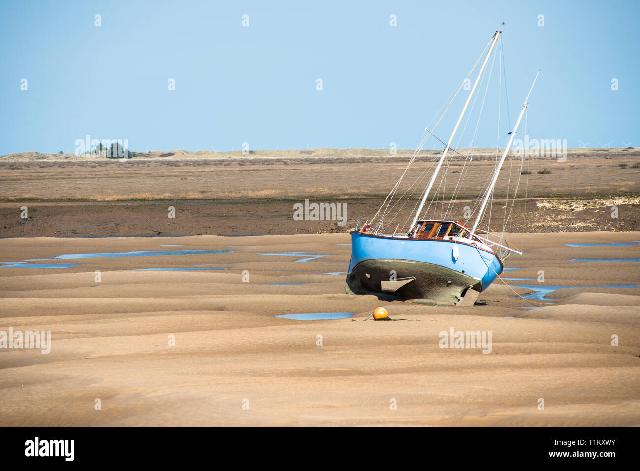 Barche colorate fregata su banchi di sabbia con la bassa marea sulla flotta est estuario del fiume a Wells accanto al mare Costa North Norfolk, East Anglia, Inghilterra, Regno Unito. Foto Stock