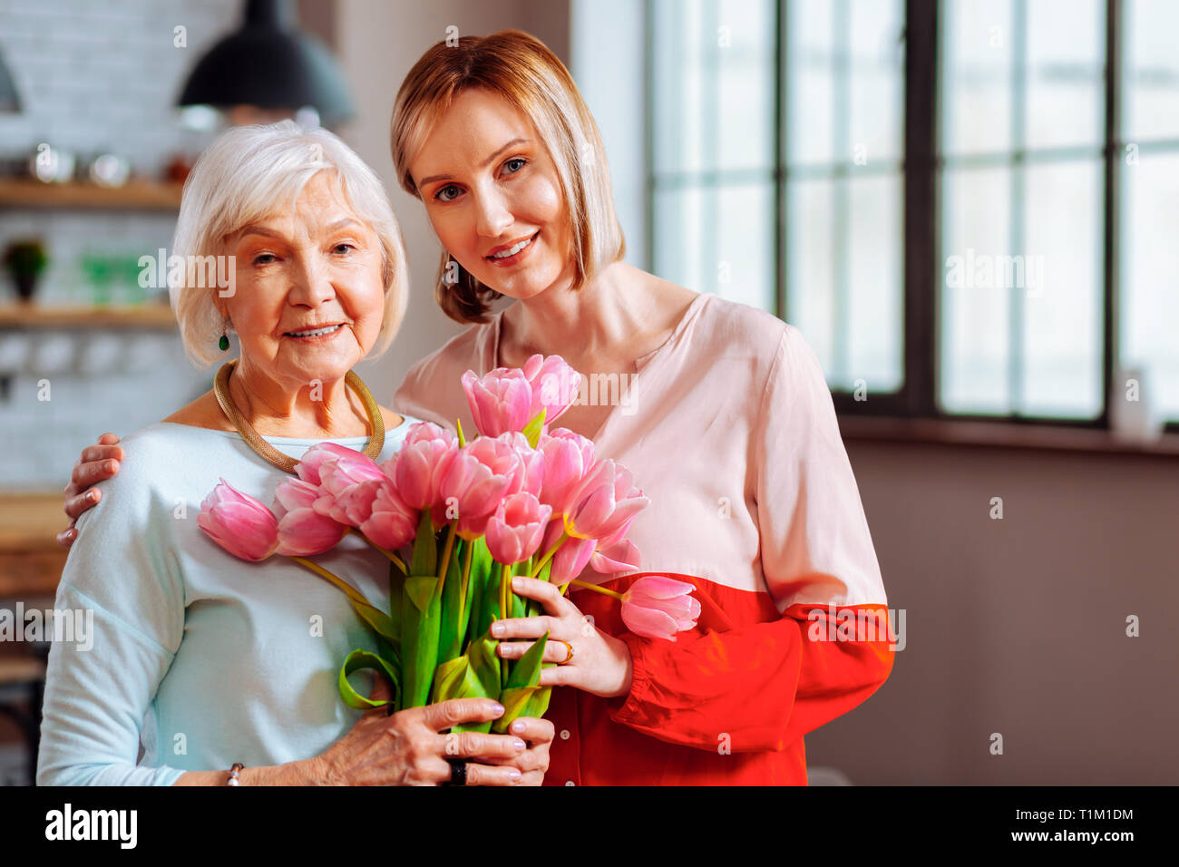 Bellissima figlia matura dando i tulipani di rugosa grigio-pelose madre Foto Stock