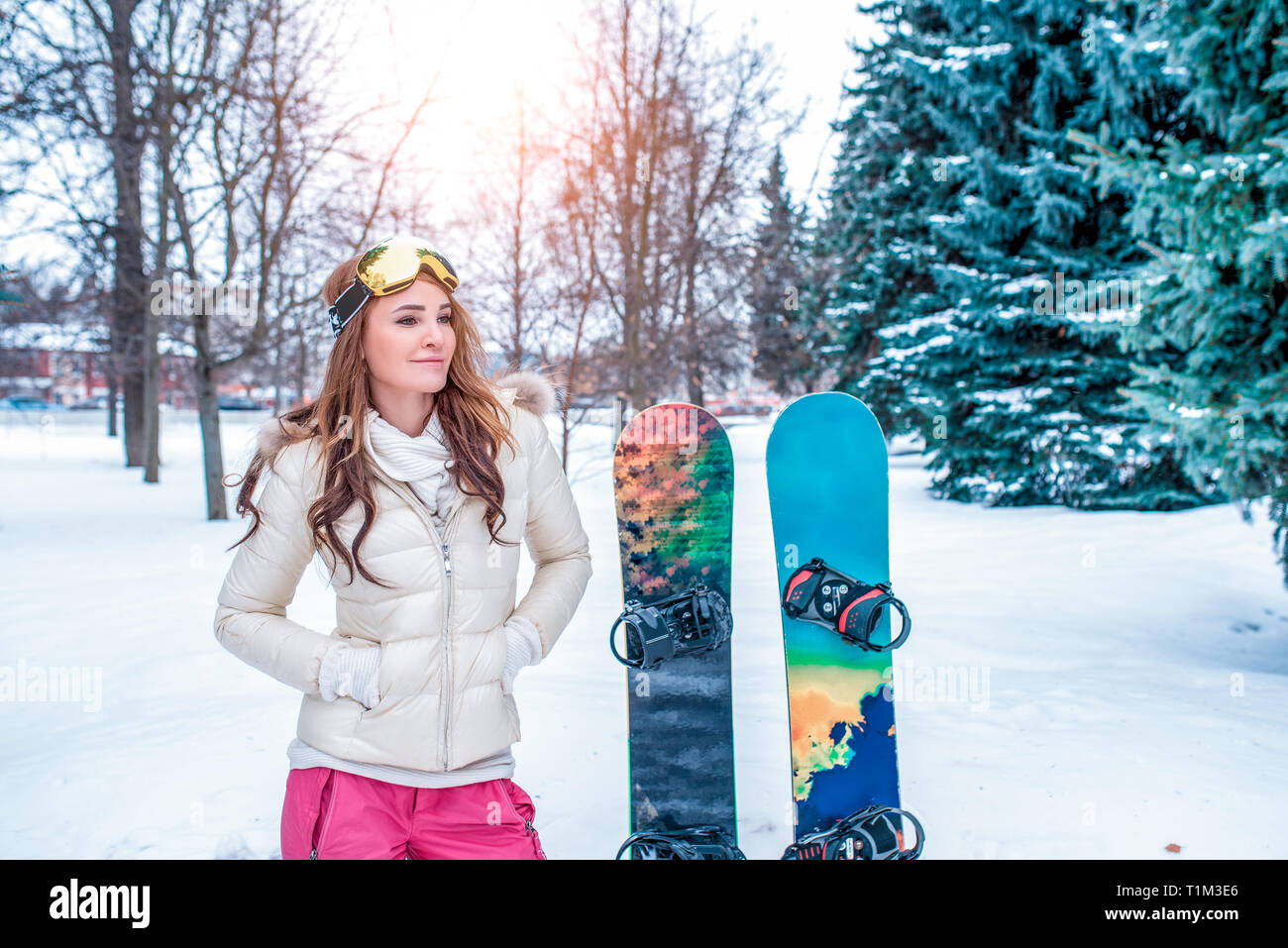Happy girl atleta, sorge in inverno nella foresta, sullo sfondo della neve  e tavole da snowboard. In bicchieri e una giacca calda tuta per la guida  Foto stock - Alamy