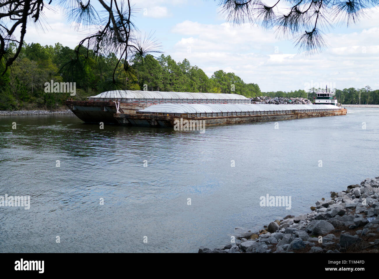 Rimorchiatore spinge una chiatta verso ovest sulla Intracoastal Waterway attraverso Orange Beach, Alabama. Foto Stock