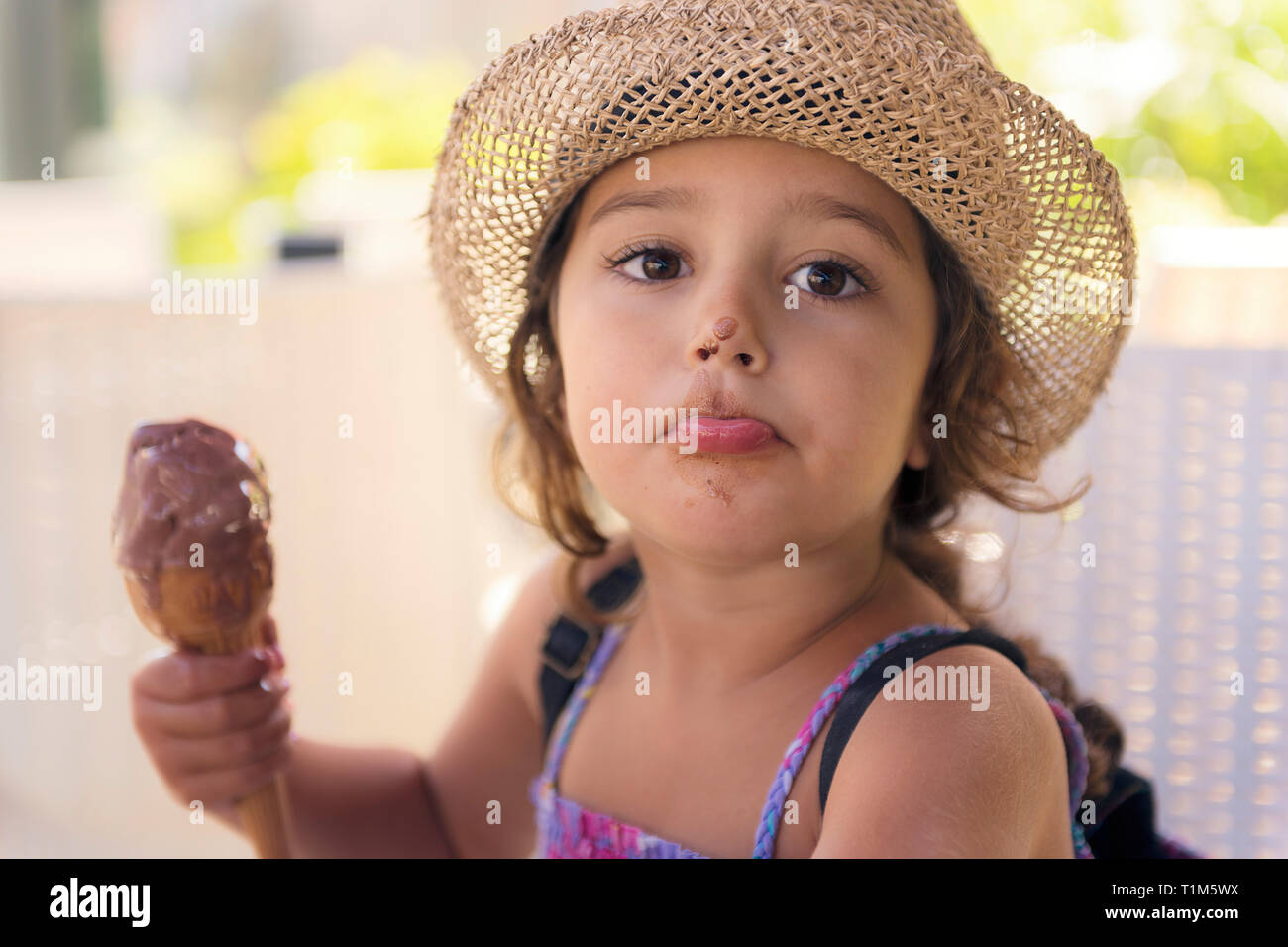 Bambina con cappello di paglia e un sundress gode il calore estivo di  mangiare un rinfrescante
