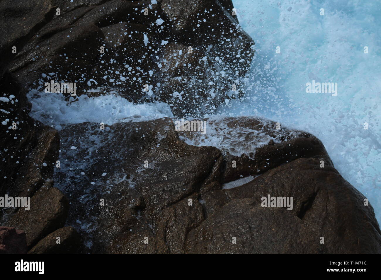 Macchie di goccioline di acqua volare in aria direttamente dopo l'onda ha schiantato contro il rock.Ho preso questo al momento giusto per catturare loro Foto Stock