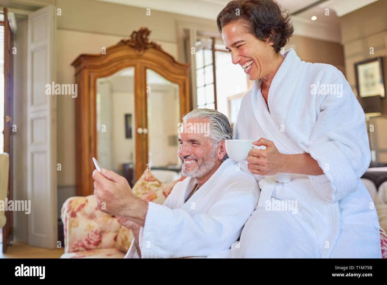 Felice Coppia matura in spa accappatoi di bere il caffè in camera di albergo Foto Stock