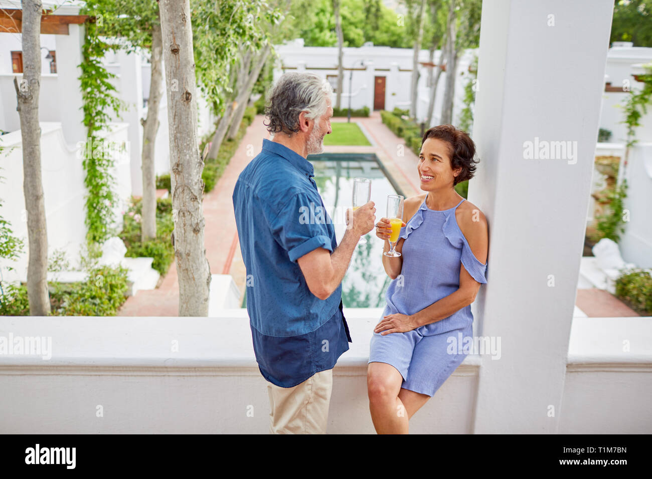 Coppia matura bere mimosas hotel sul balcone Foto Stock