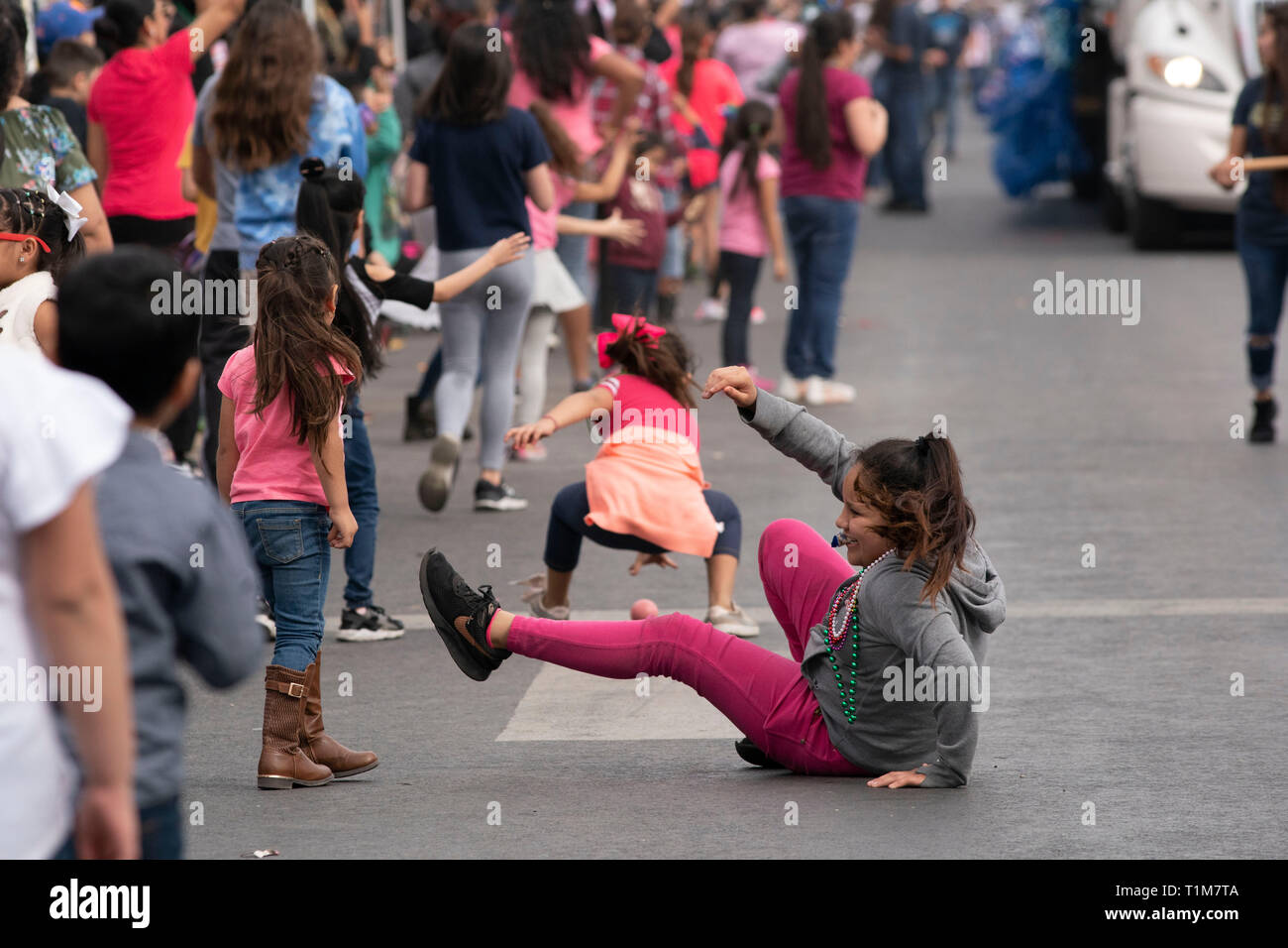 Bambini scramble di agguantare la caramella e perle gettato da galleggianti su strada nel corso annuale di Washington la celebrazione di compleanno sfilata nel centro cittadino di Laredo TX. Foto Stock