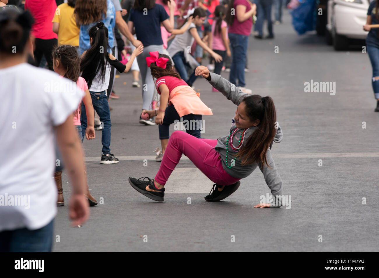 Bambini scramble di agguantare la caramella e perle gettato da galleggianti su strada nel corso annuale di Washington la celebrazione di compleanno sfilata nel centro cittadino di Laredo TX. Foto Stock