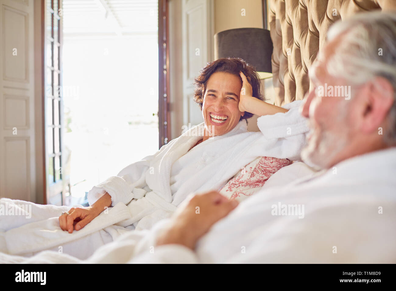 Felice, ridendo coppia matura relax su hotel bed Foto Stock