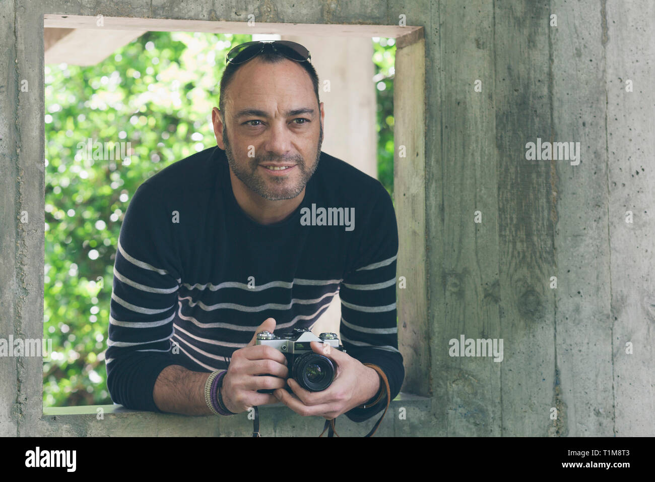 Ritratto uomo con la fotocamera in piedi nella finestra sul giardino Foto Stock