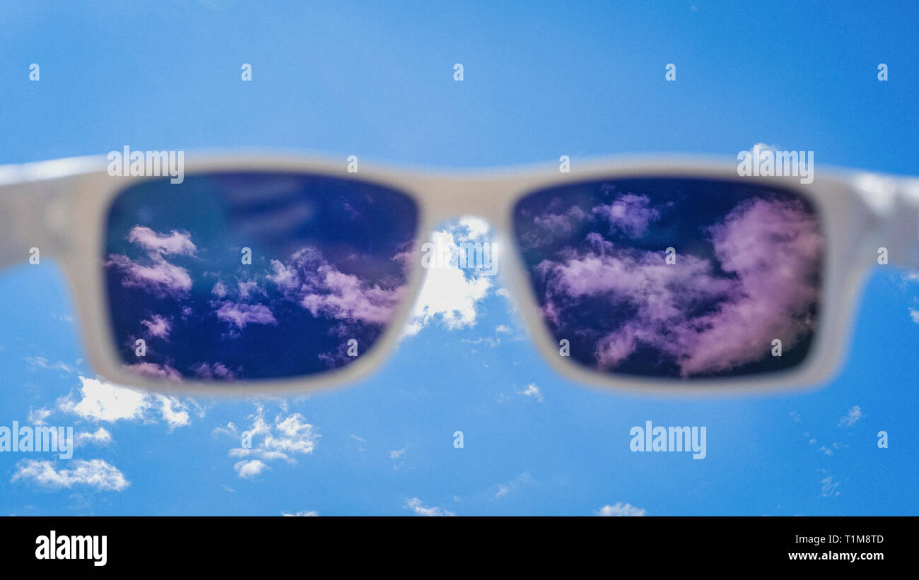 Punto di vista personale occhiali da sole guardando il sole cielo blu con nuvole Foto Stock