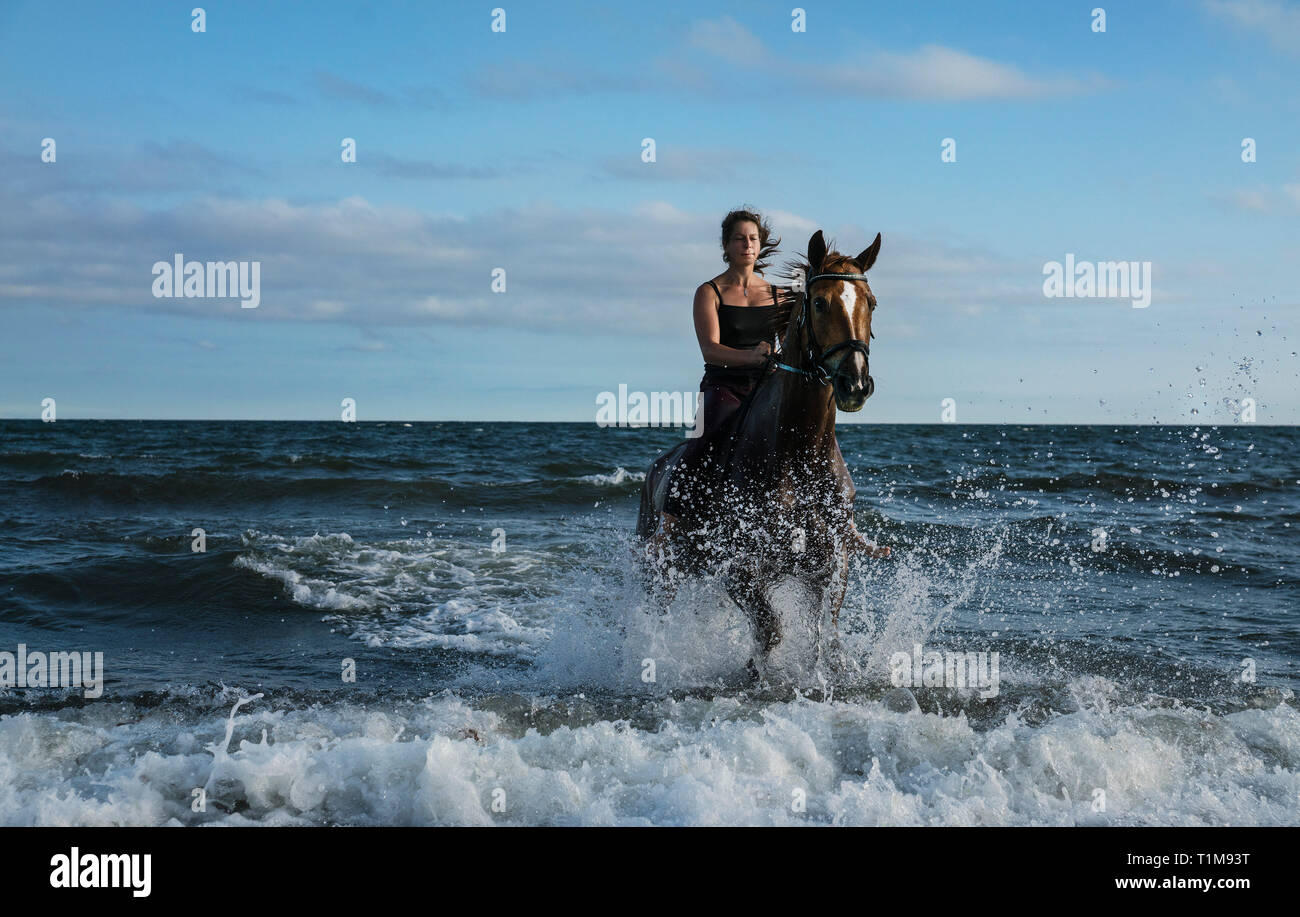 Donna di equitazione in ocean surf Foto Stock